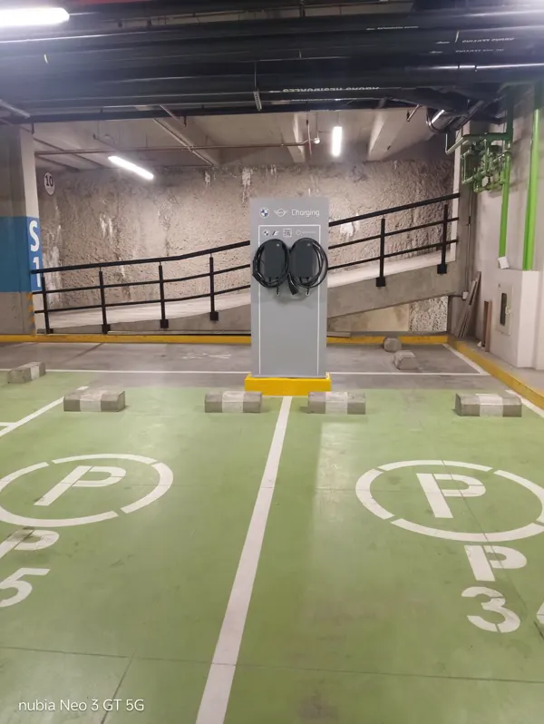 Estación de carga comunal con bahías demarcadas para vehículos eléctricos