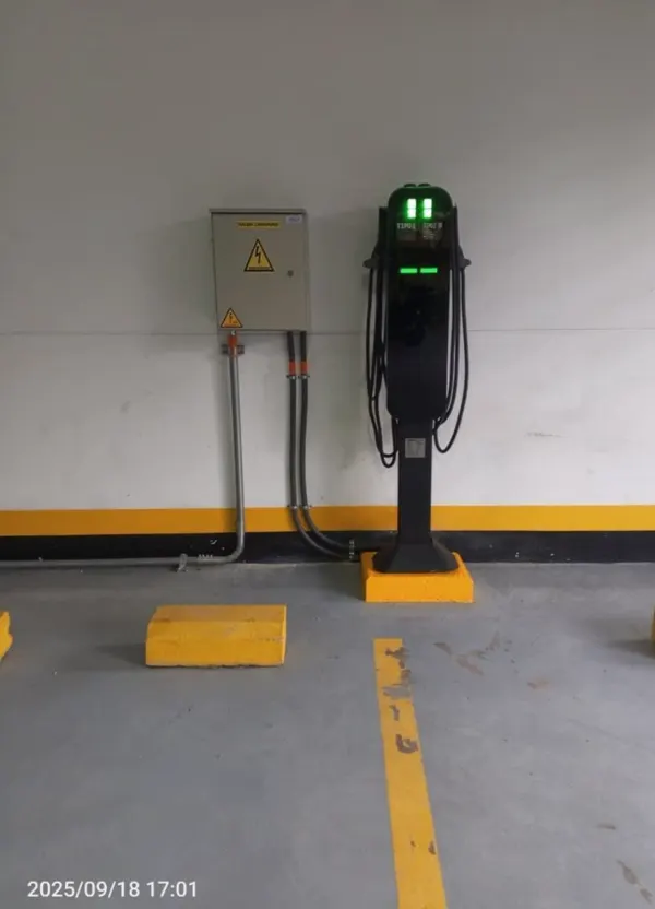 Cargador sobre pedestal en parqueadero demarcado con tablero de protecciones