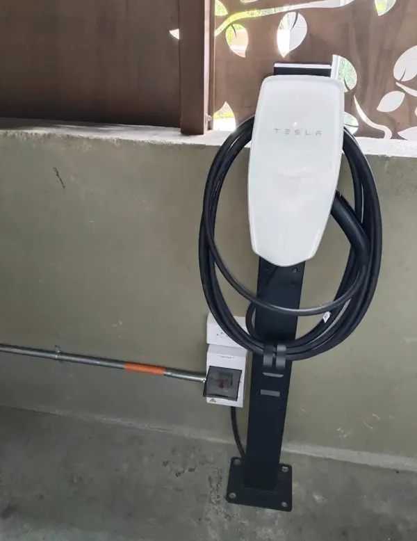 Tesla Wall Connector instalado sobre pedestal en parqueadero residencial